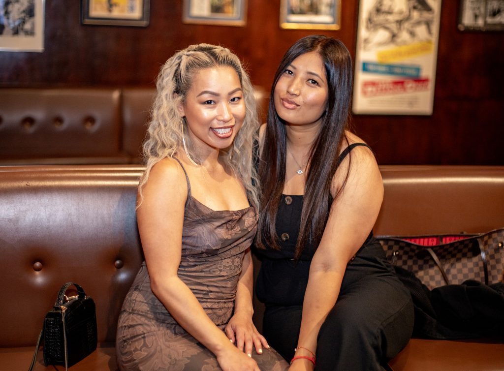 two women sitting on a couch together wearing dresses