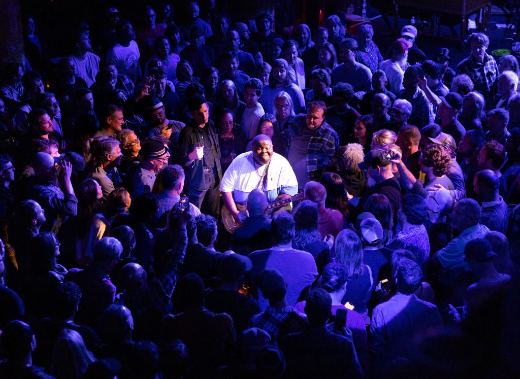 kingfish playing guitar in the middle of a crowd